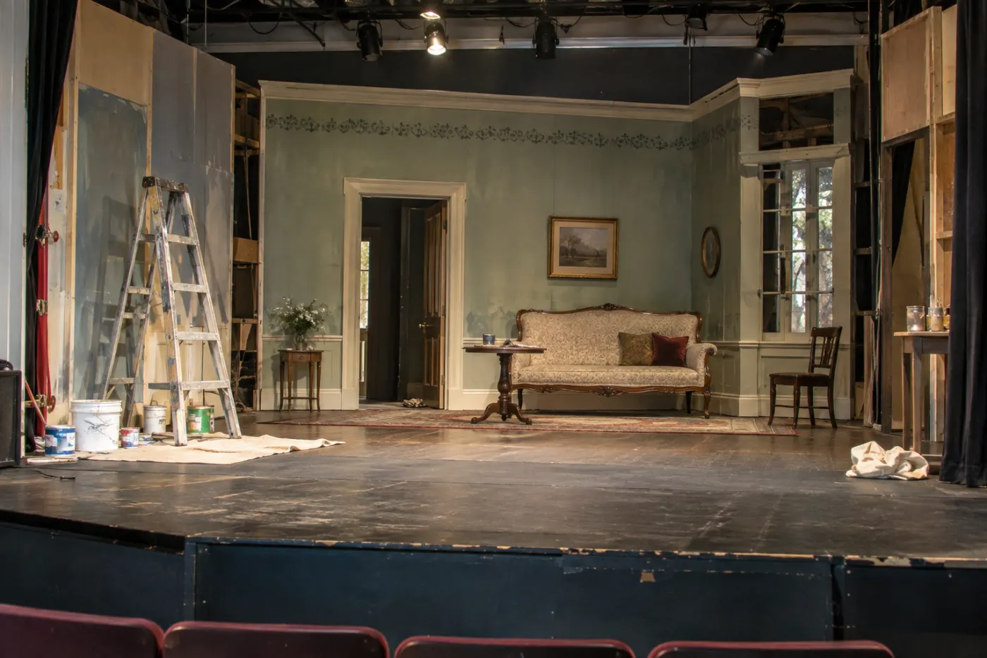 The drawing-room set for The Importance of Being Earnest on the stage, a ladder and paint cans still at the edge